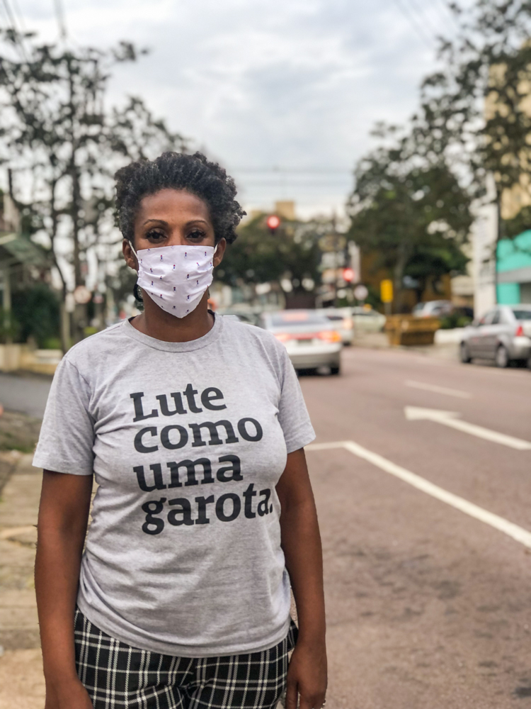 Andreia olhando para a câmera em uma rua de Curitiba. 