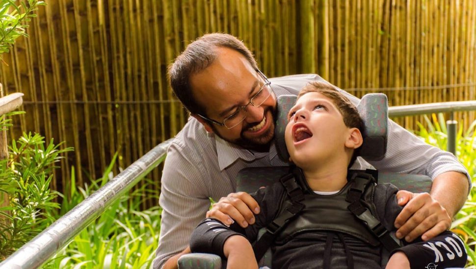 Pai e filho com paralisia cerebral abraçados