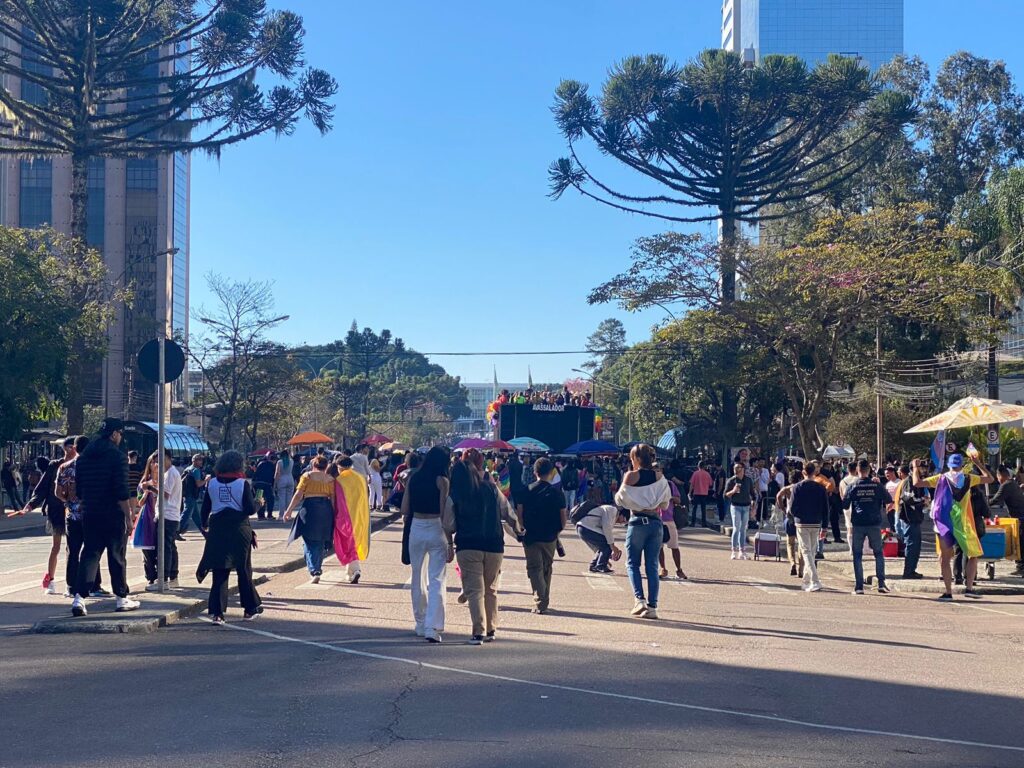 pessoas caminhando pela rua usando bandeiras LGBT